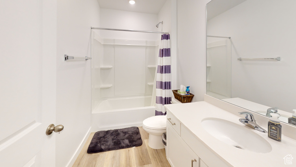 Full bathroom with hardwood / wood-style flooring, shower / bath combination with curtain, toilet, and vanity