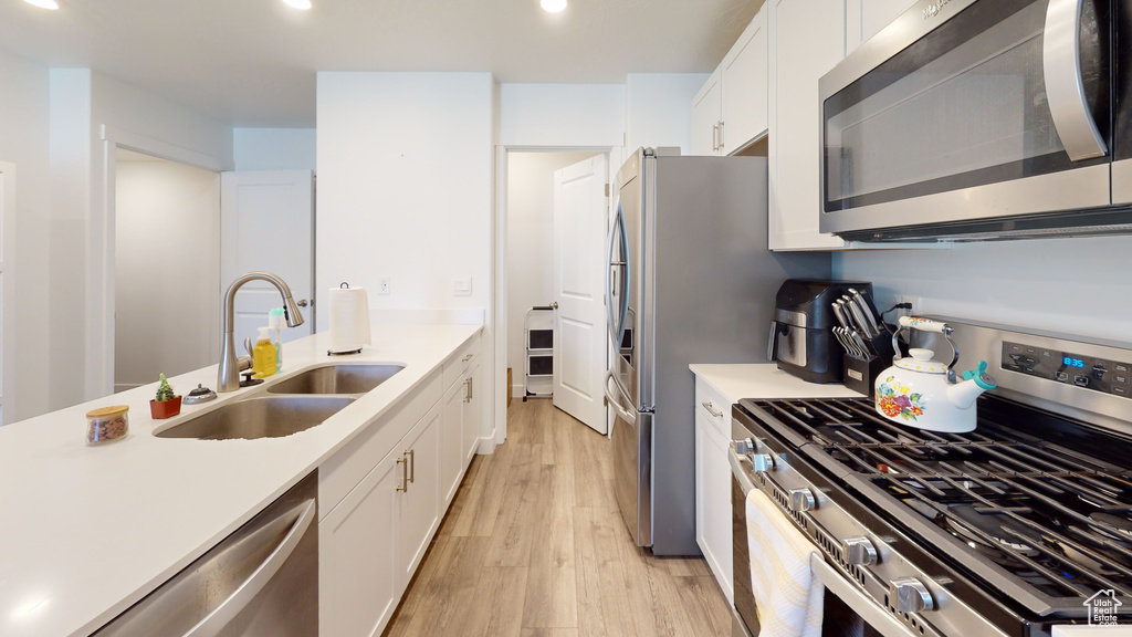 Kitchen featuring white cabinets, stainless steel appliances, light hardwood / wood-style floors, and sink