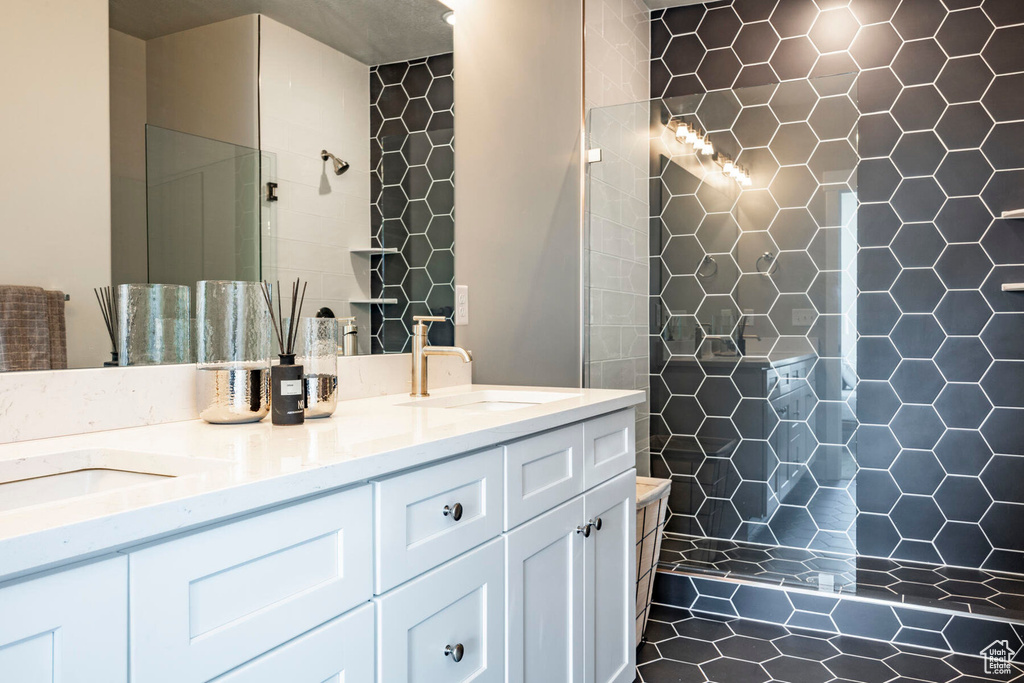 Bathroom featuring tiled shower and double vanity