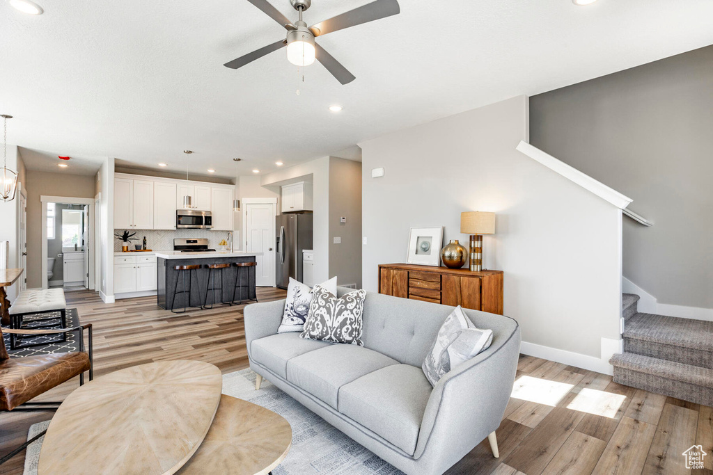 Living room with ceiling fan and light hardwood / wood-style floors