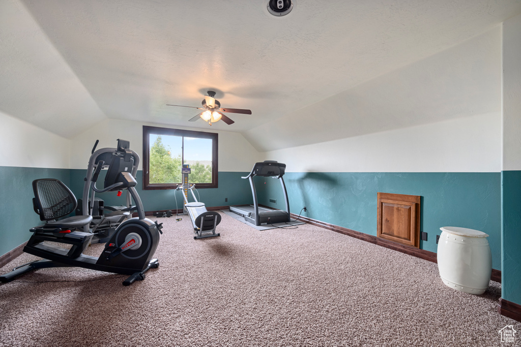 Exercise area with carpet flooring, a textured ceiling, vaulted ceiling, and ceiling fan