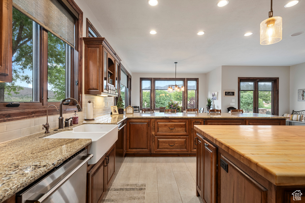 Kitchen featuring dishwasher, butcher block counters, backsplash, and decorative light fixtures