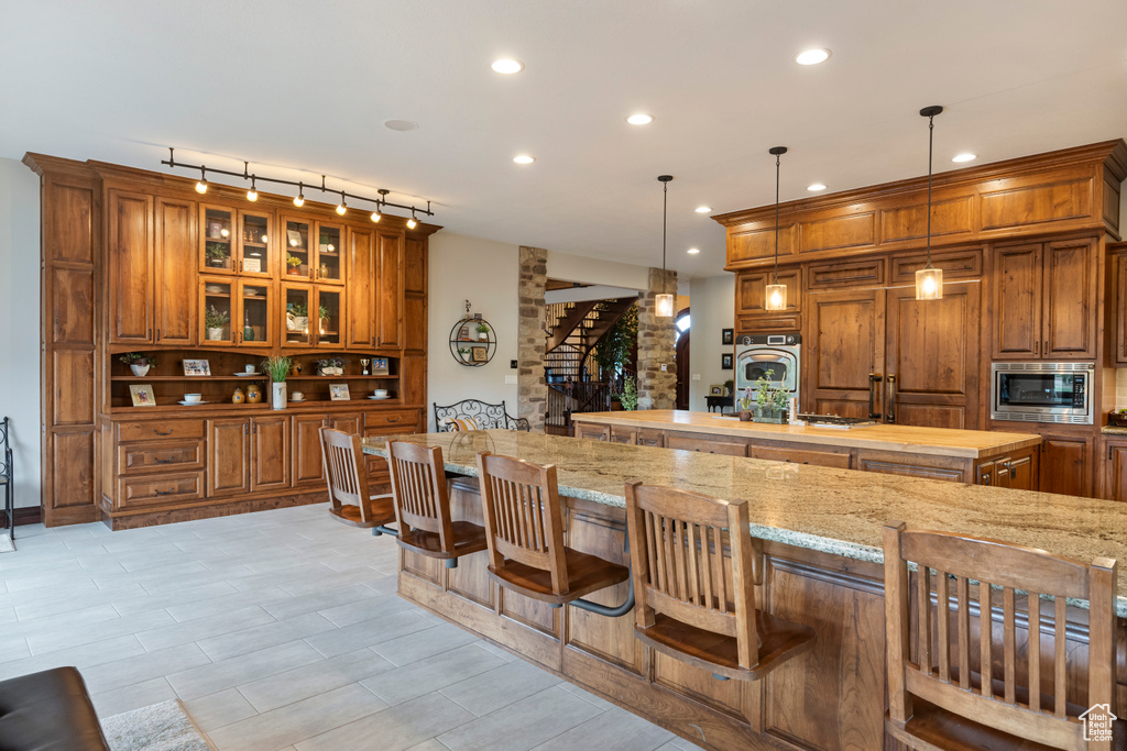 Kitchen featuring a breakfast bar, light stone countertops, hanging light fixtures, and stainless steel appliances