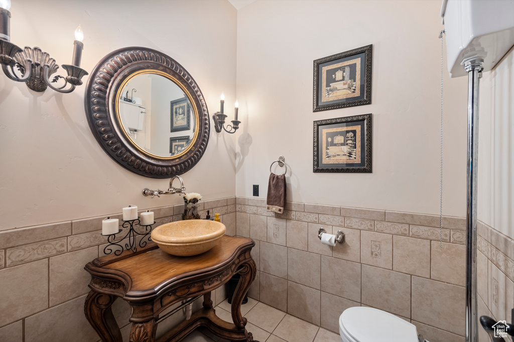 Bathroom with tile walls, tile patterned floors, toilet, and vanity