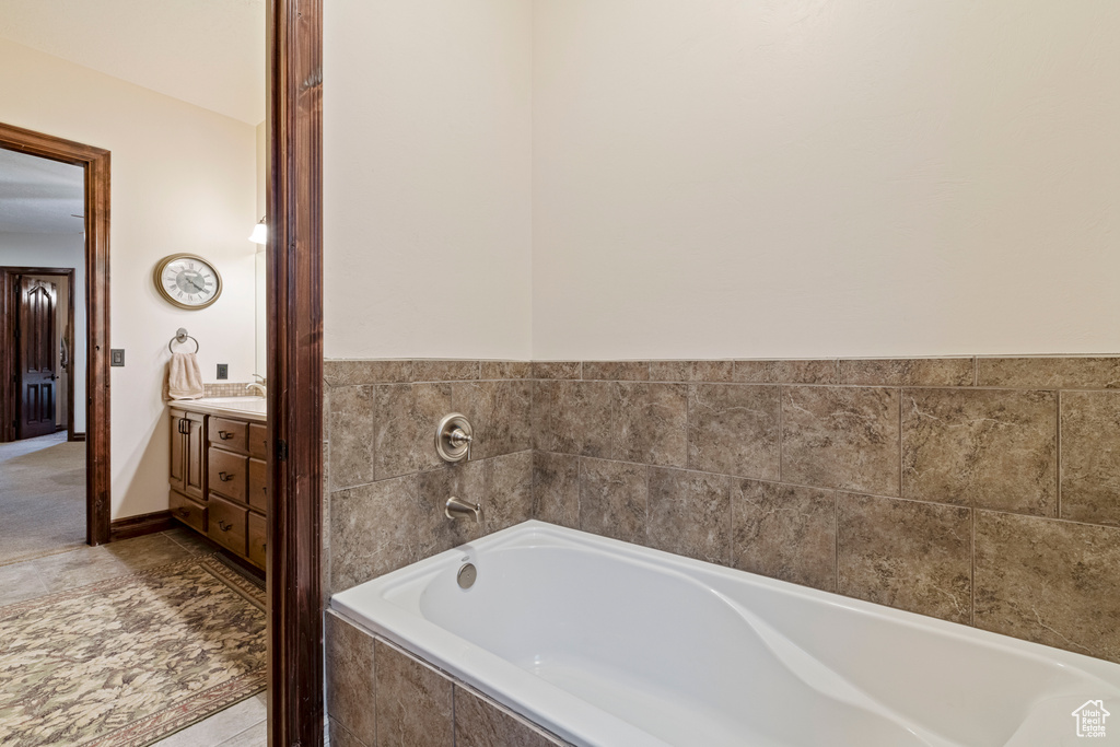 Bathroom featuring vanity, tiled tub, and tile patterned floors