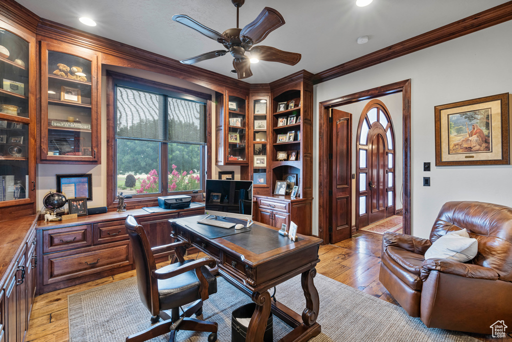 Office space with ornamental molding, light hardwood / wood-style flooring, built in features, and ceiling fan