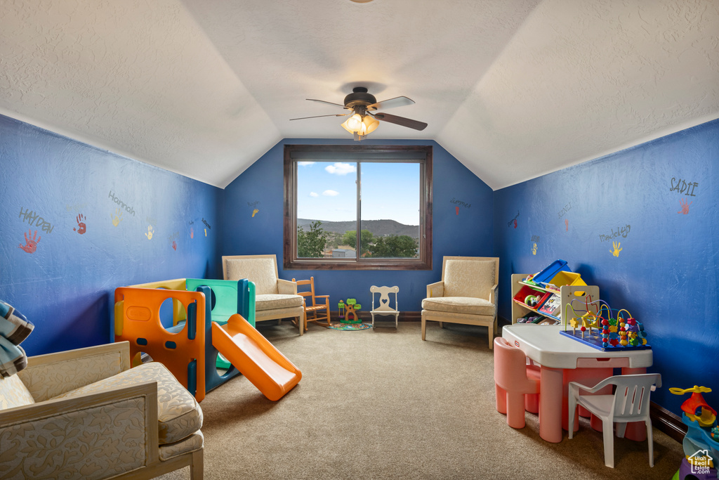 Recreation room featuring carpet floors, a textured ceiling, ceiling fan, and vaulted ceiling