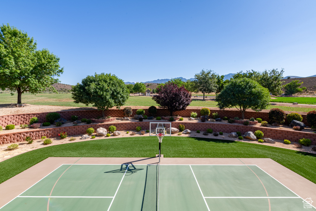 View of tennis court featuring a mountain view, basketball court, and a lawn