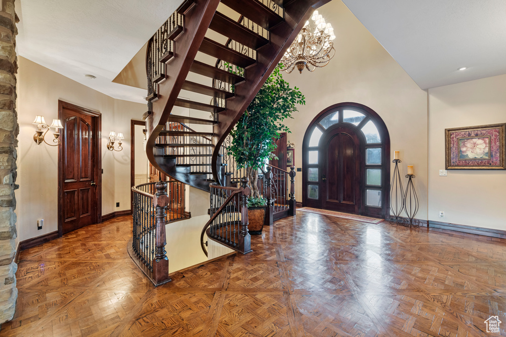 Entrance foyer with parquet flooring, a notable chandelier, and a towering ceiling