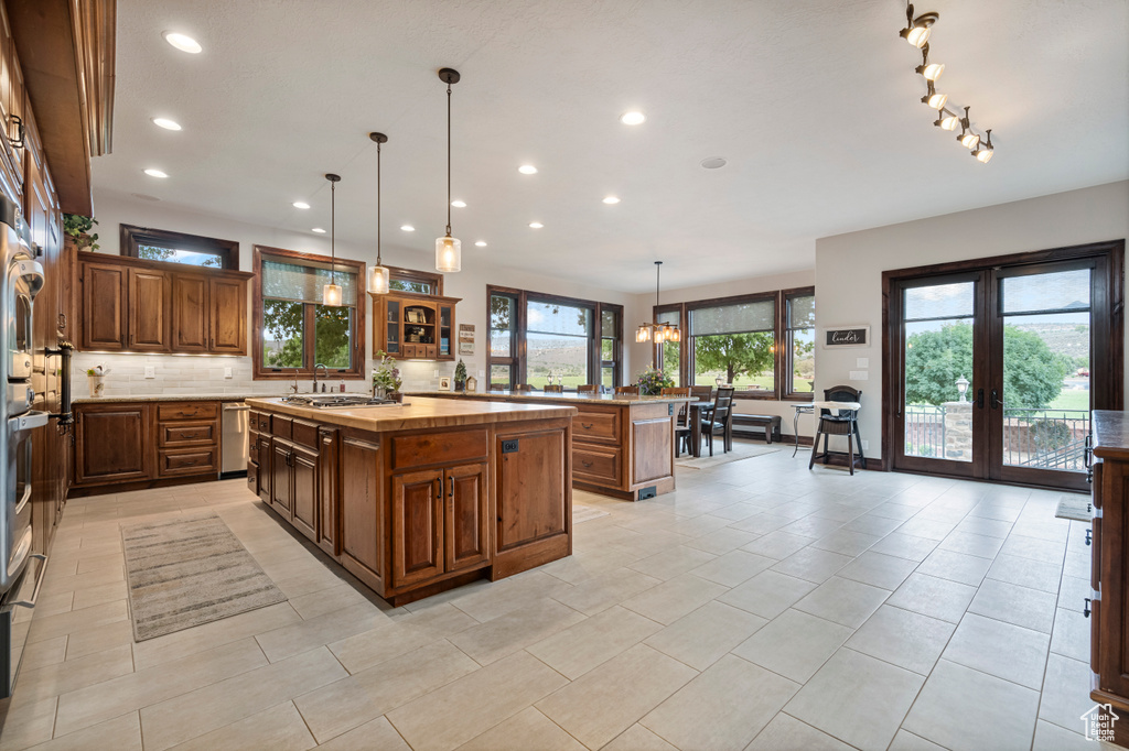 Kitchen with butcher block countertops, french doors, light tile patterned floors, stainless steel dishwasher, and a center island