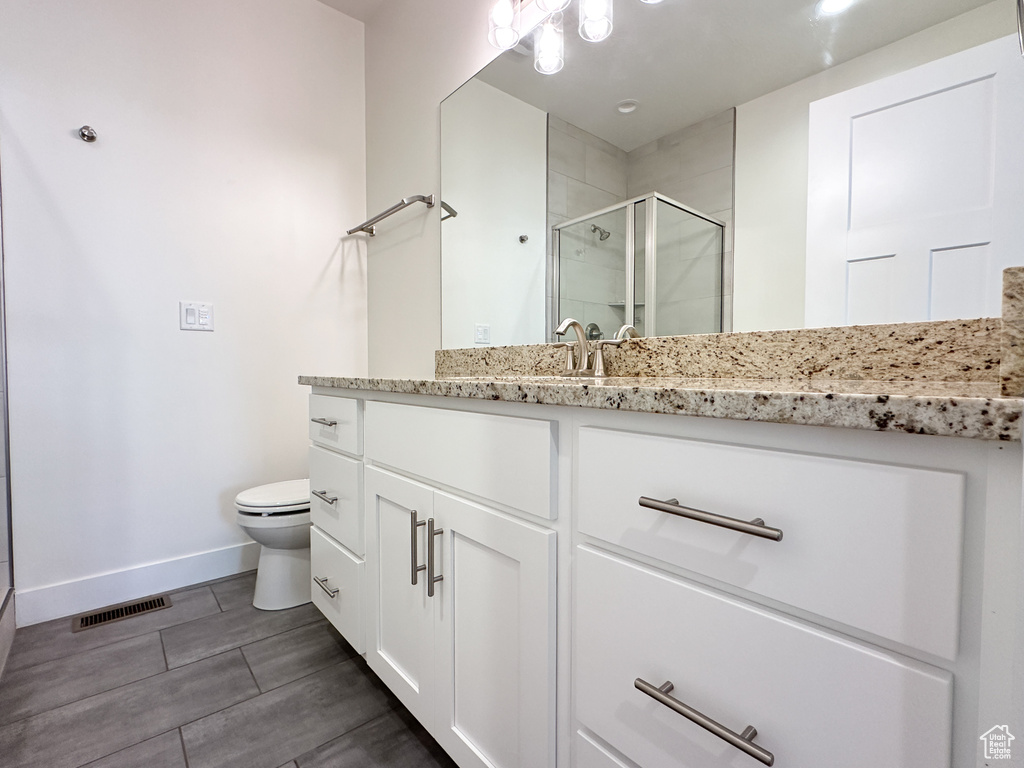 Bathroom featuring a shower with shower door, toilet, and vanity