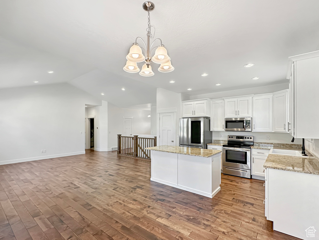 Kitchen with decorative light fixtures, light hardwood / wood-style flooring, appliances with stainless steel finishes, sink, and white cabinetry