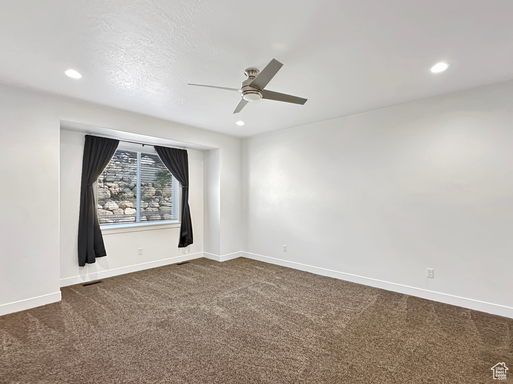 Carpeted spare room with a textured ceiling and ceiling fan