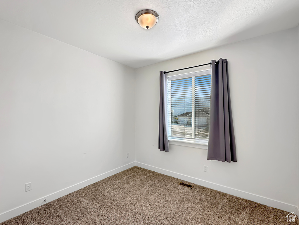 Spare room featuring a textured ceiling and carpet