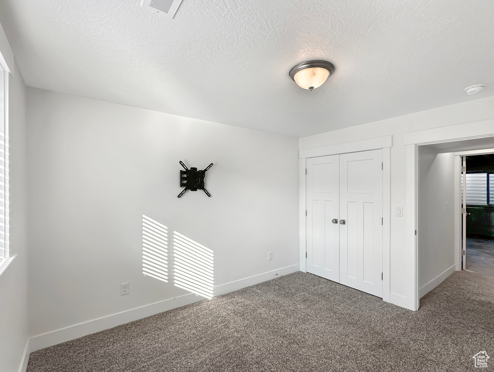 Unfurnished bedroom with a textured ceiling, carpet, and a closet