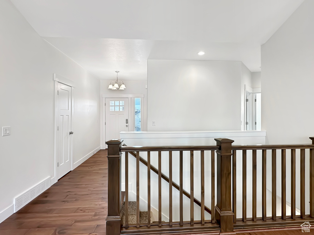 Corridor with an inviting chandelier and dark hardwood / wood-style floors