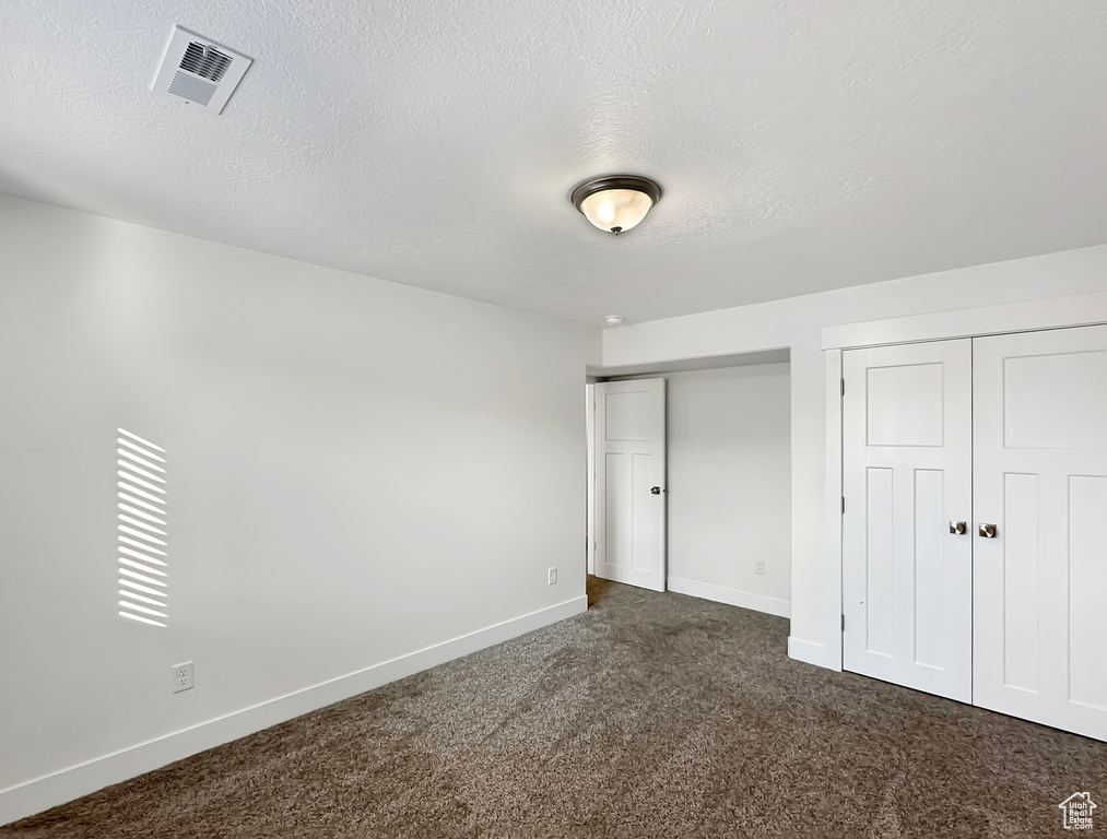 Unfurnished bedroom featuring a textured ceiling and carpet