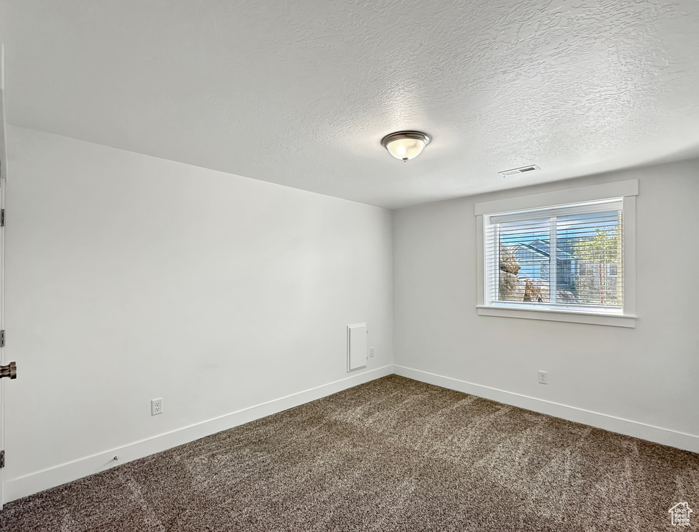 Spare room featuring a textured ceiling and carpet