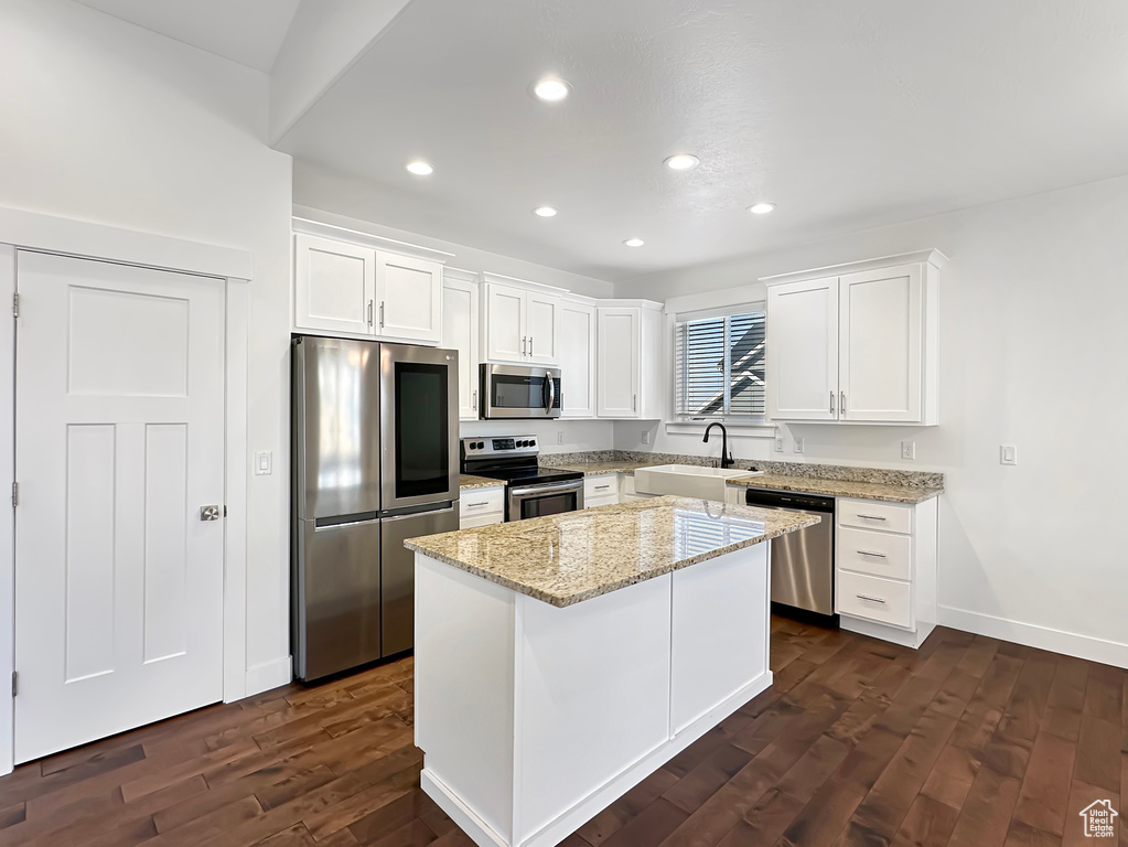 Kitchen with dark wood-type flooring, stainless steel appliances, sink, a center island, and white cabinets