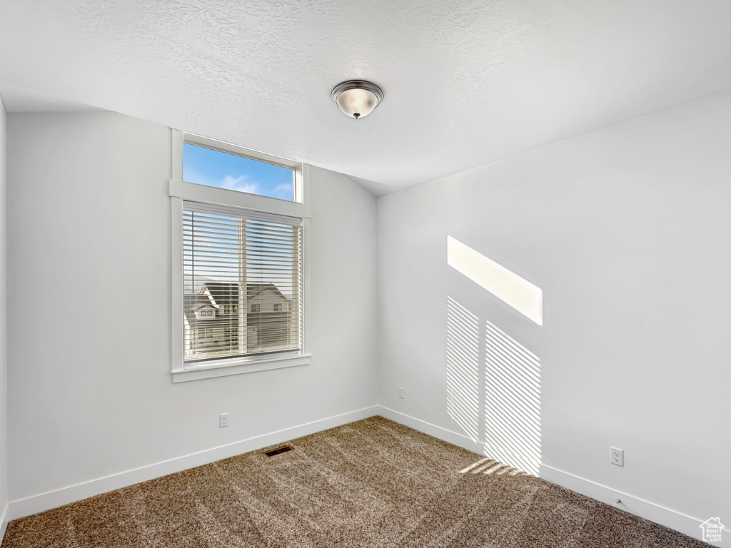 Empty room with a textured ceiling and carpet