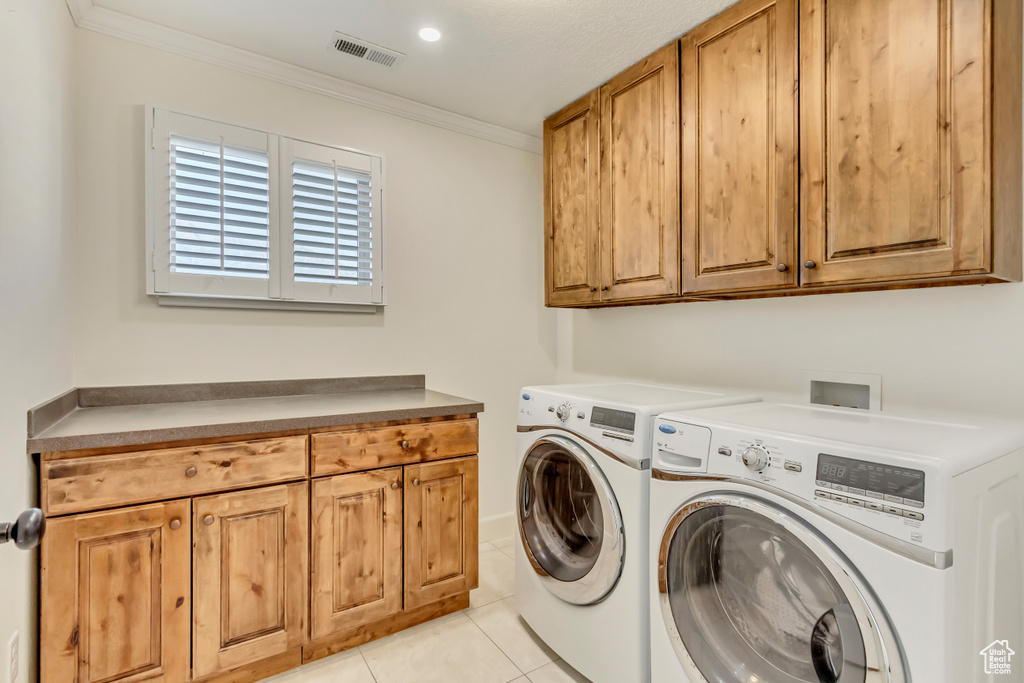 Washroom featuring light tile patterned flooring, washer and dryer, crown molding, and cabinets