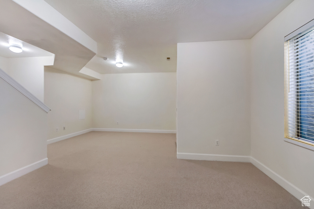 Basement with a textured ceiling and light colored carpet