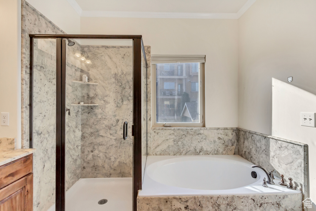 Bathroom with ornamental molding, vanity, and separate shower and tub