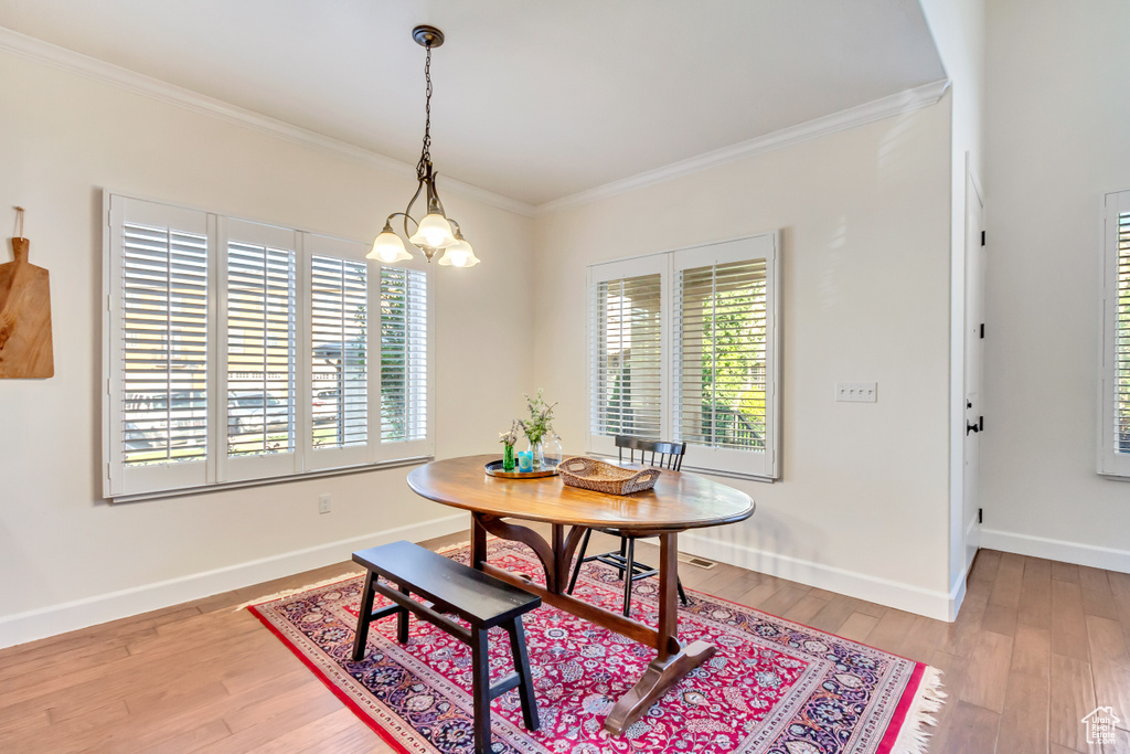 Dining space featuring plenty of natural light, a chandelier, light hardwood / wood-style flooring, and ornamental molding