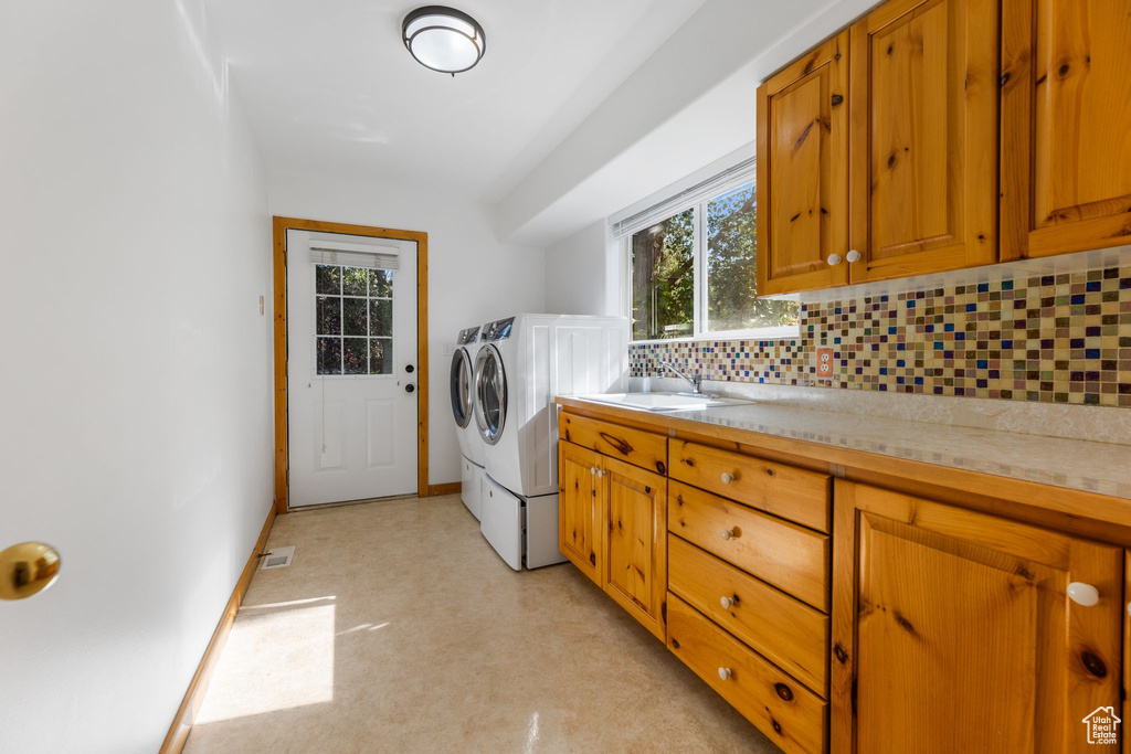 Laundry room featuring sink, cabinets, and independent washer and dryer