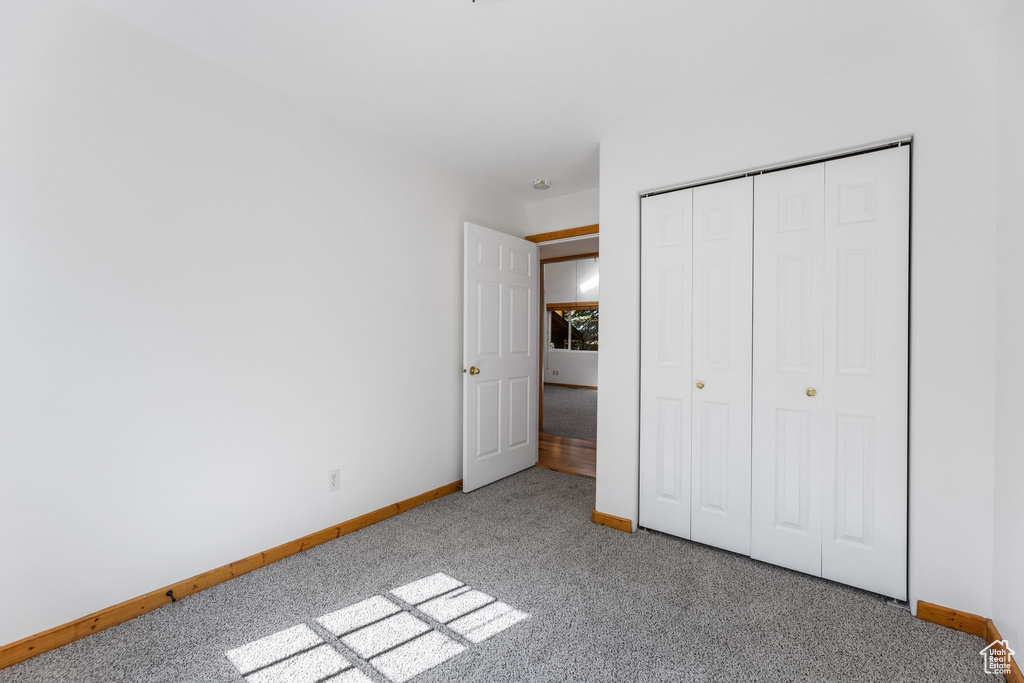 Unfurnished bedroom with light carpet and a closet