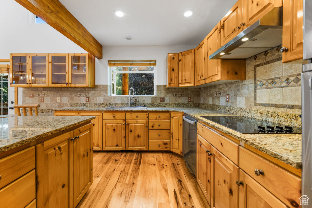 Kitchen featuring tasteful backsplash, sink, light stone counters, light hardwood / wood-style floors, and black electric stovetop