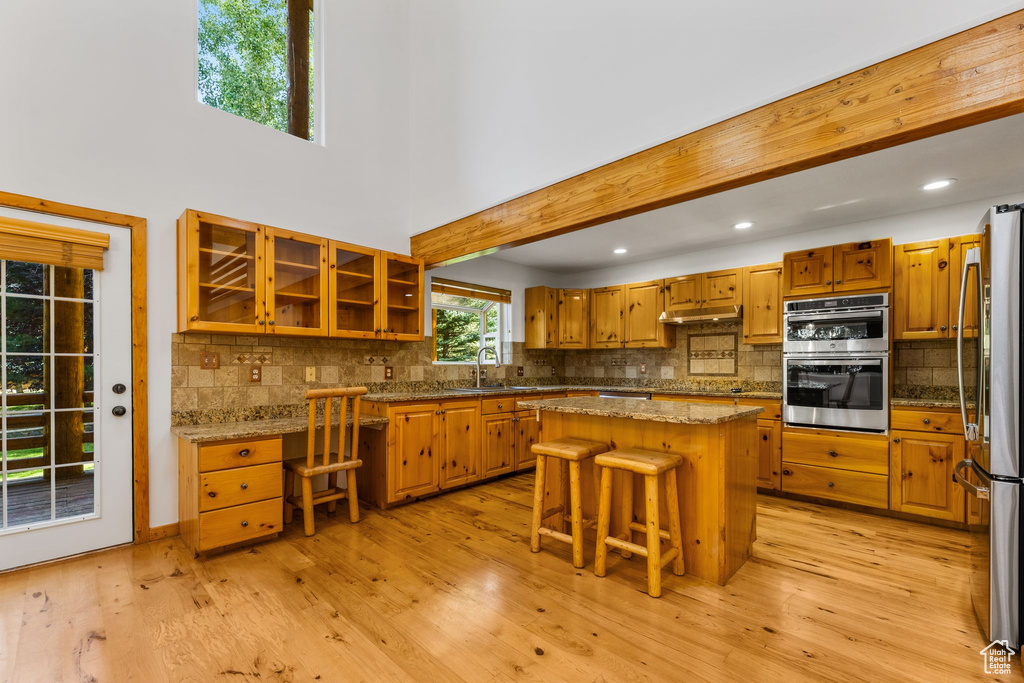 Kitchen with a kitchen breakfast bar, a center island, tasteful backsplash, and light wood-type flooring