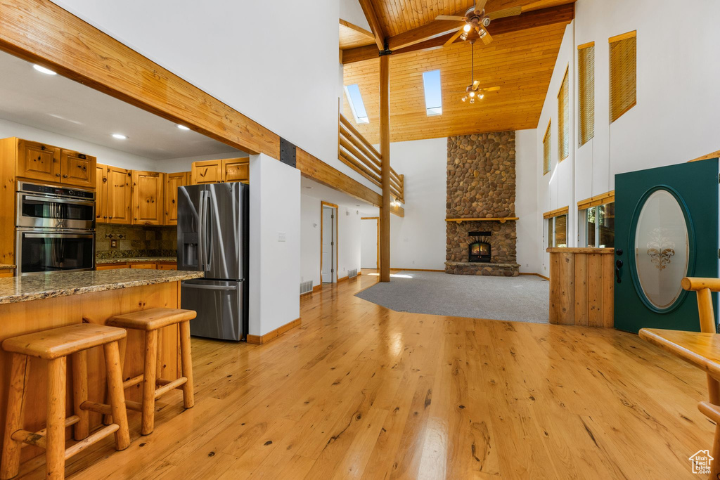 Kitchen with appliances with stainless steel finishes, light hardwood / wood-style flooring, a fireplace, backsplash, and ceiling fan