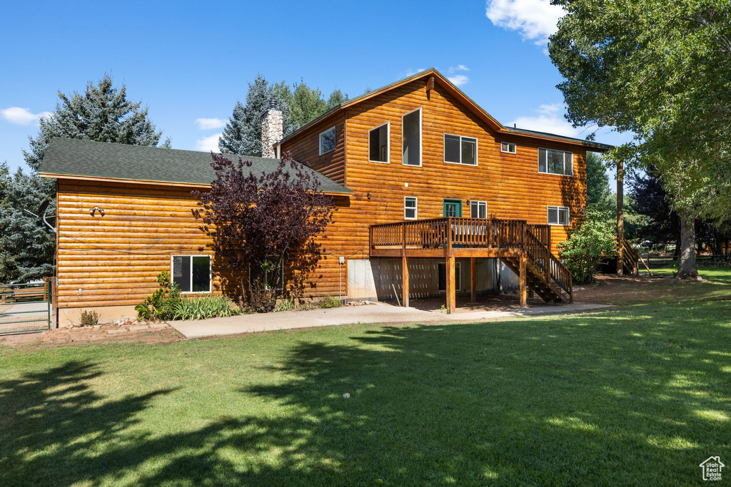 Back of property featuring a wooden deck and a lawn