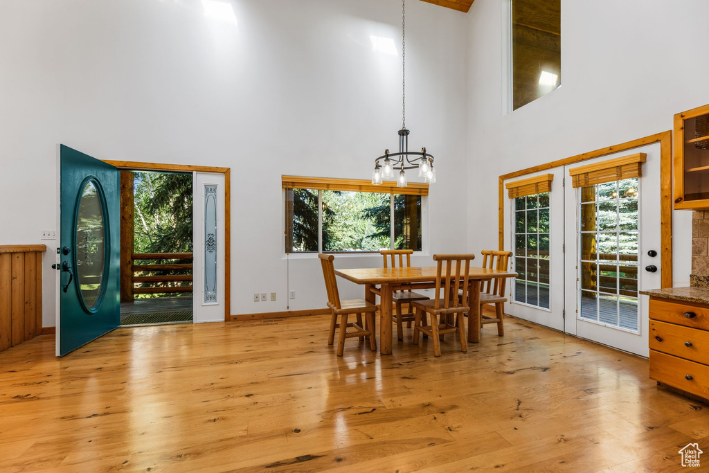 Dining room featuring a notable chandelier, light hardwood / wood-style flooring, plenty of natural light, and a towering ceiling