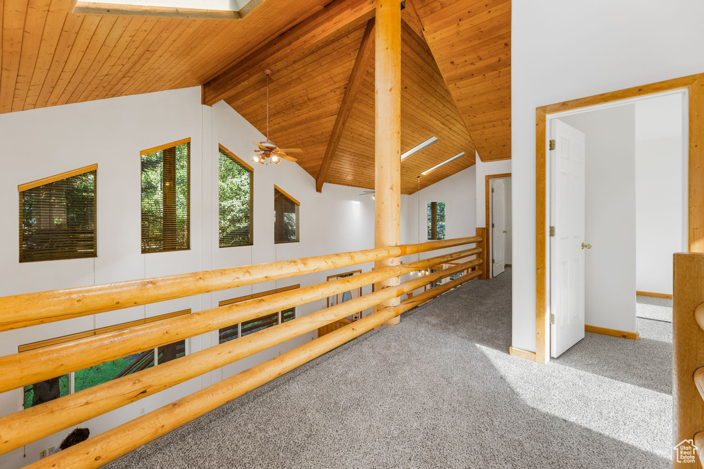 Empty room with carpet flooring, vaulted ceiling with beams, wood ceiling, and ceiling fan