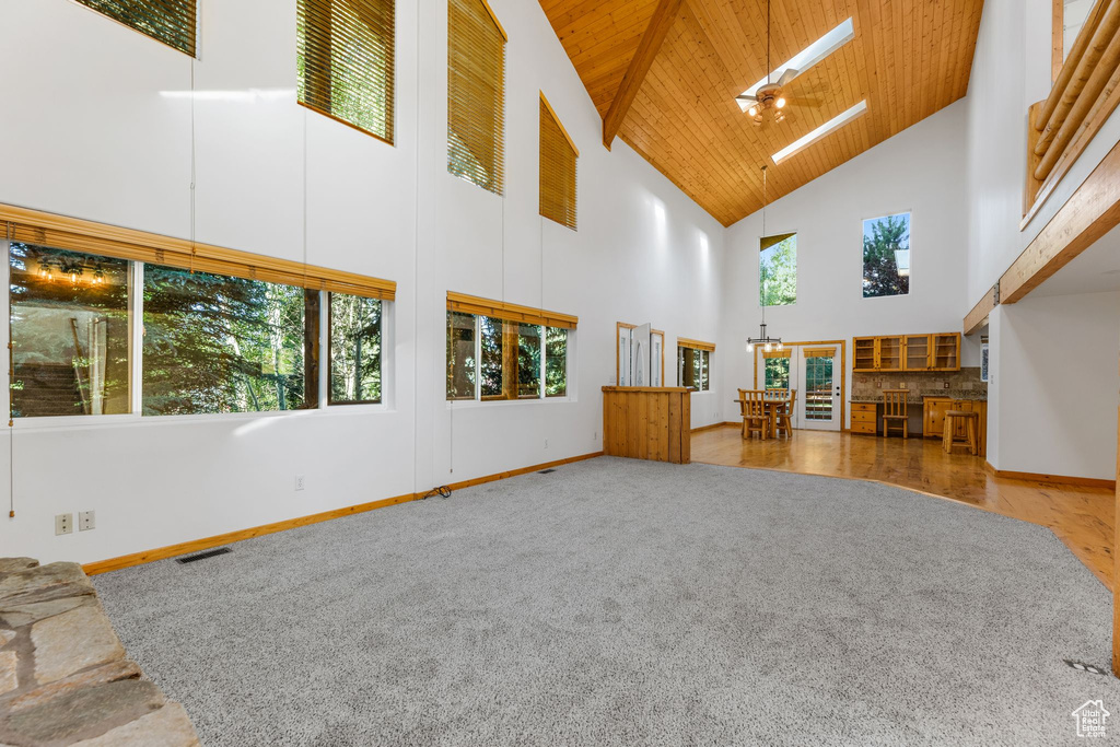 Unfurnished living room with wooden ceiling, light hardwood / wood-style flooring, a chandelier, and high vaulted ceiling