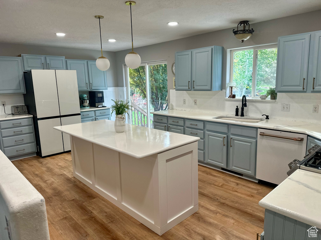 Kitchen with plenty of natural light, stainless steel dishwasher, sink, and white refrigerator