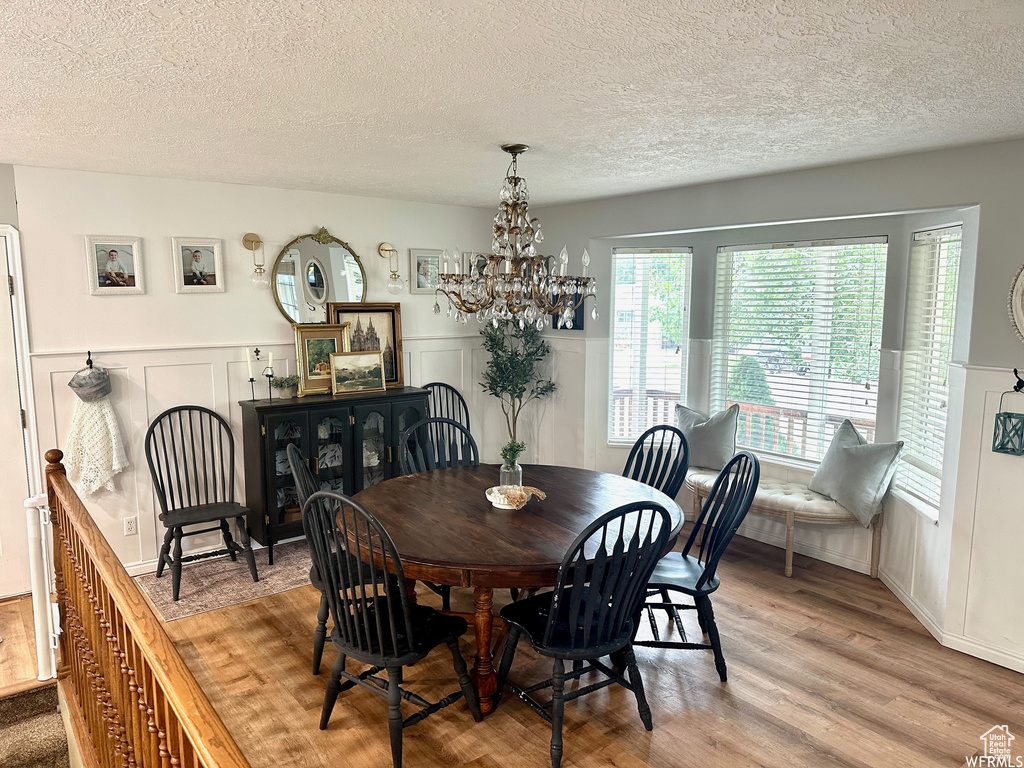 Dining room featuring a textured ceiling, a notable chandelier, and light hardwood / wood-style floors