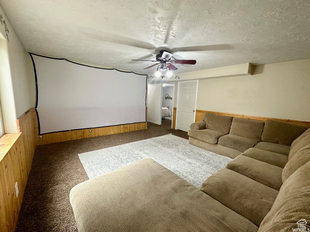 Carpeted home theater featuring a textured ceiling and ceiling fan