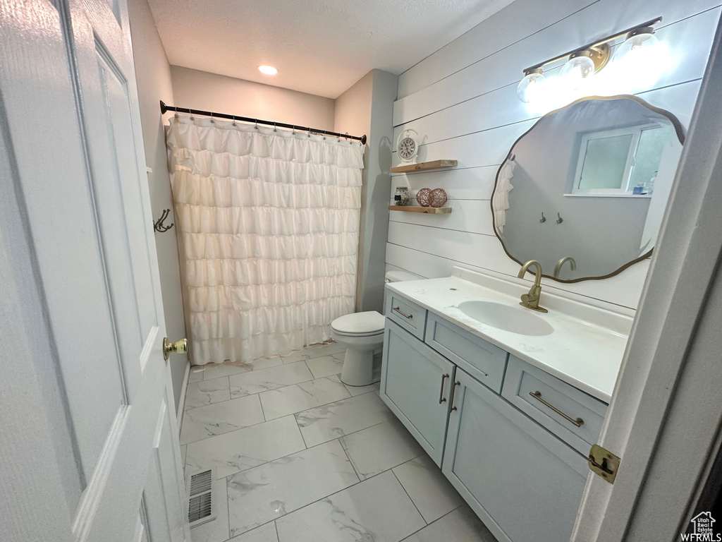 Bathroom featuring wood walls, vanity, tile patterned flooring, and toilet