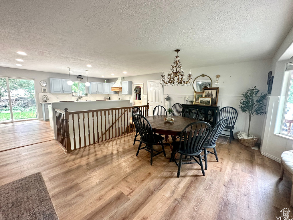 Dining room featuring light hardwood / wood-style floors, a notable chandelier, and a textured ceiling