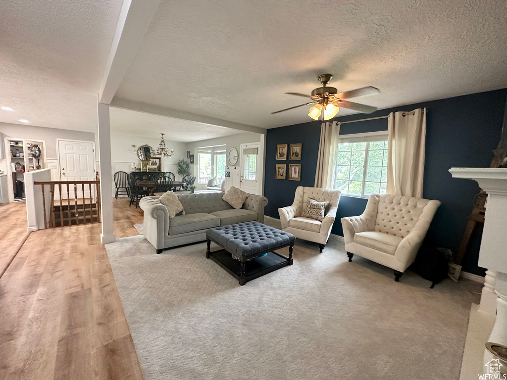 Living room with a fireplace, light hardwood / wood-style floors, a textured ceiling, and ceiling fan