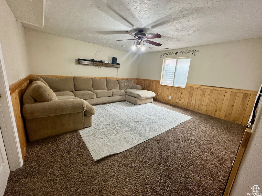 Living room with carpet flooring, a textured ceiling, and ceiling fan