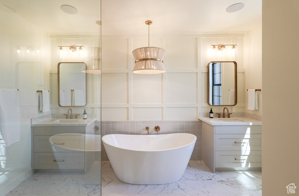 Bathroom with tile patterned flooring, a bath, dual bowl vanity, and tile walls