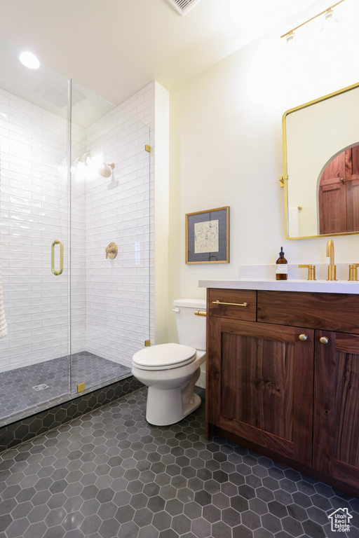 Bathroom featuring vanity, toilet, tile patterned flooring, and an enclosed shower