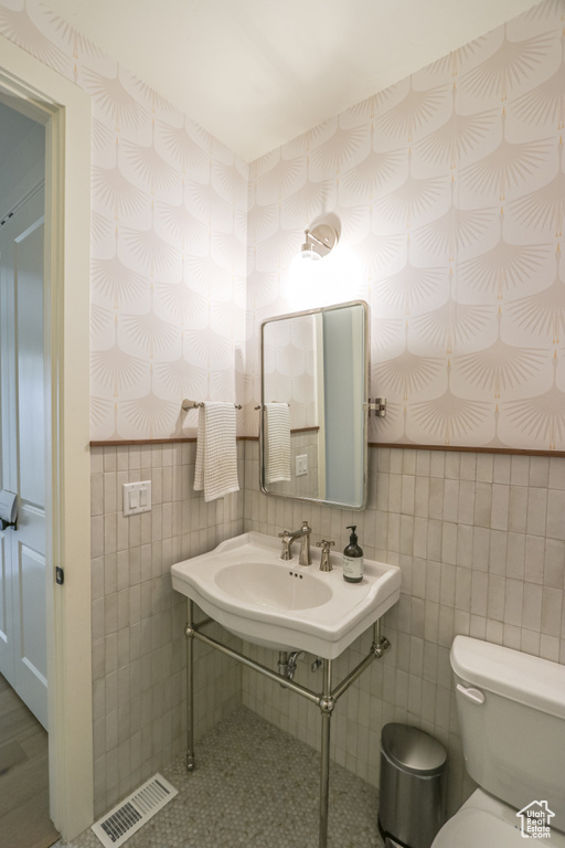 Bathroom with toilet, backsplash, and tile walls