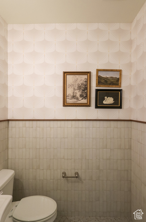 Bathroom featuring tile walls and toilet