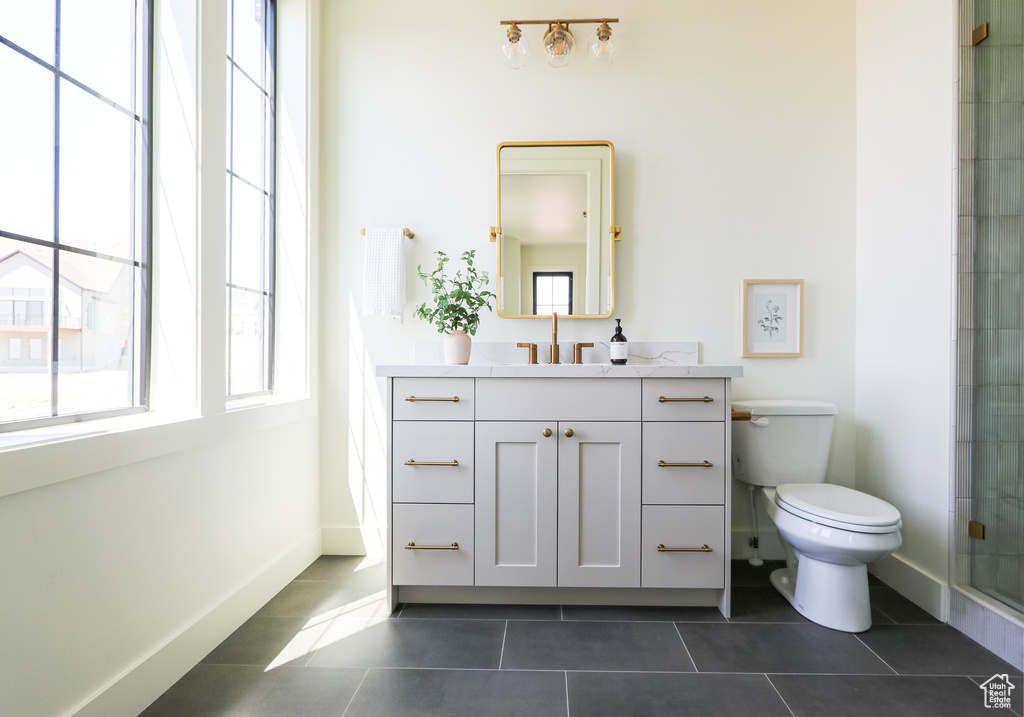 Bathroom featuring an enclosed shower, vanity, tile patterned floors, and toilet