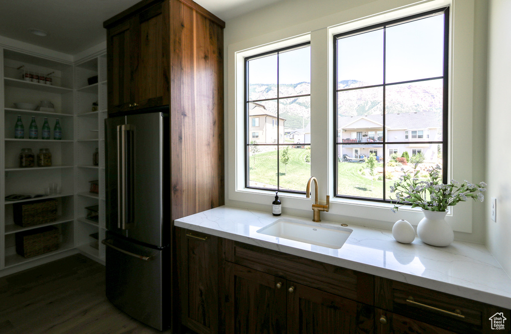 Kitchen featuring sink, dark hardwood / wood-style floors, light stone counters, and stainless steel fridge